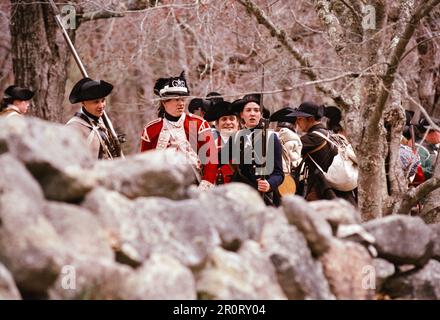 Lexington, Massachusetts, USA - April 2023: Im Minuteman National Histori stoßen koloniale und britische Truppen auf Musketen, die auf der Battle Road schießen Stockfoto