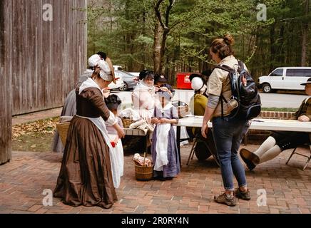 Lexington, Massachusetts, USA - April 2023: Ein Besucher hält an, um sich mit Frauen und Kindern zu unterhalten, die hinter dem Minuteman N in Kolonialkleidung gekleidet sind Stockfoto