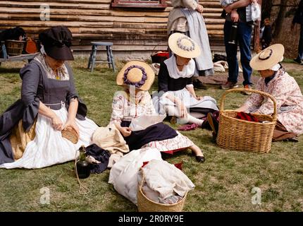 Lexington, Massachusetts, USA - April 2023 - Frauen und Kinder sitzen auf dem Rasen vor dem Haus von Captain William Smith im Minuteman National Stockfoto