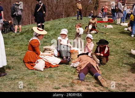 Lexington, Massachusetts, USA - April 2023 - Frauen und Kinder sitzen auf dem Rasen vor dem Haus von Captain William Smith im Minuteman National Stockfoto