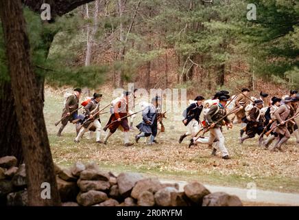 Lexington, Massachusetts, USA - April 2023: Im Minuteman National Histori stoßen koloniale und britische Truppen auf Musketen, die auf der Battle Road schießen Stockfoto