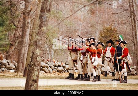 Lexington, Massachusetts, USA - April 2023: Im Minuteman National Histori stoßen koloniale und britische Truppen auf Musketen, die auf der Battle Road schießen Stockfoto