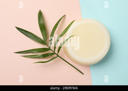 Durchgehender Shampoo-Streifen und grünes Blatt auf farbigem Hintergrund, Draufsicht. Haarpflege Stockfoto