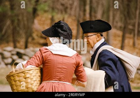 Lexington, Massachusetts, USA - April 2023: Eine Frau und ein Mann, die ihr Eigentum im Minuteman National Historical Park Dura die Battle Road hinunter tragen Stockfoto