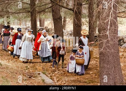 Lexington, Massachusetts, USA - April 2023 - Frauen und Kinder im Kolonialstil spazieren mit all ihren Gegenständen auf der Schlachtstraße in Minutenschnelle Stockfoto