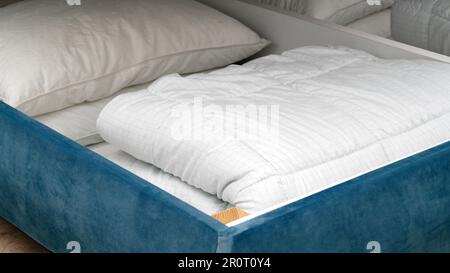 Schublade unter dem Bett mit weißer Decke und Kissen im Innenbereich, Schließfach Stockfoto