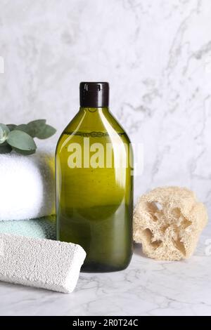 Shampooflasche, Luffa, gefaltete Handtücher und Bimsstein auf weißem Marmortisch Stockfoto