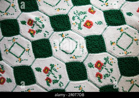 Großmutters gestrickte oder grün-weiße Bettdecke lässt Sie an Omas Haus denken. Es ist gemütlich und warm, ideal für einen kranken Tag Stockfoto