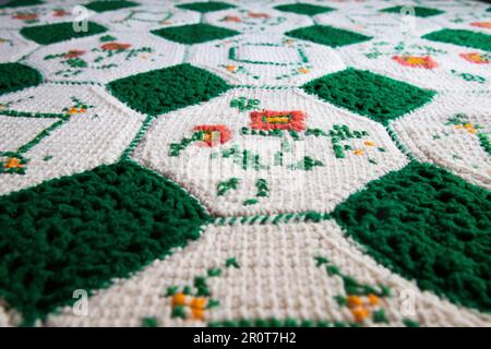 Nahaufnahme von Omas gestrickter oder gestrickter grün-weißer Decke. Diese Decke lässt Sie an Omas Haus denken. Es ist gemütlich und warm, großartig Stockfoto