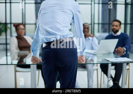 Junger Mitarbeiter, der um Rat von seinen hilfsbereiten, erfahrenen Kollegen im Büro bittet Stockfoto
