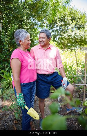 Wie ihr Garten wächst auch ihre Liebe. Ein glückliches Seniorenpaar, das zusammen im Garten gärtnert. Stockfoto