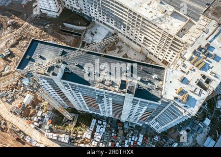 Kranarbeiten an Unterbauten in Hochhausgebäuden. Luftdrohnenfoto mit Blick nach unten. Stockfoto