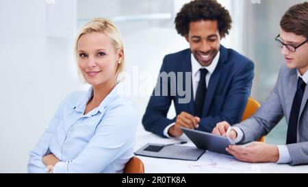 Ich habe die Arbeit getan, um meine Ziele zu erreichen. Eine selbstbewusste Geschäftsfrau mit Kollegen hinter sich. Stockfoto