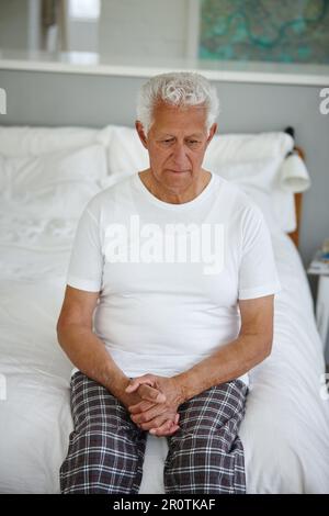 Mir blieb nichts mehr übrig... ein älterer Mann, der verzweifelt aussah, während er auf seinem Bett in einer betreuten Wohneinrichtung saß. Stockfoto