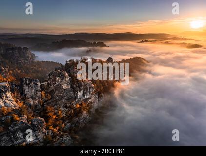 Sachsen, Deutschland - Panoramablick auf die Bastei an einem nebligen Herbstmorgen mit bunten Herbstlaub und starkem Nebel unter den Felsformationen Stockfoto