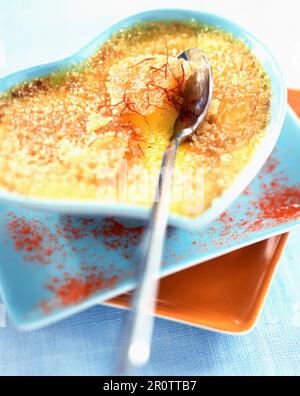 Crème brûlée mit Safran in einem herzförmigen Gericht Stockfoto