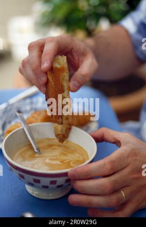Brot in weißen Kaffee eintauchen Stockfoto