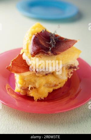 Polentarischer, herzhafter Kuchen mit zwei Käsesorten und im Ofen gebackenem rohem Schinken Stockfoto