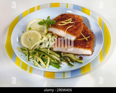 Eskalationen paniert mit Lebkuchenkrümeln und Zucchini-Julienne mit Zitrone Stockfoto