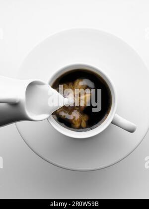Hinzufügen von Milch zu einer Tasse Kaffee Stockfoto