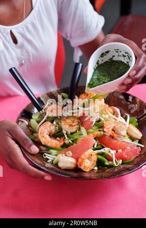 Das Dressing auf den Salat gießen Stockfoto