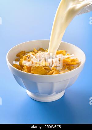 Milch in eine Schüssel Cornflakes gießen Stockfoto