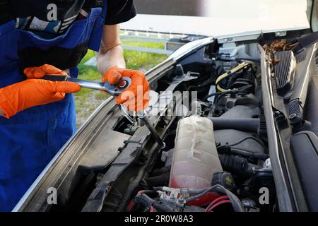 Mechaniker, der einen Motor repariert. Ein Mann repariert ein kaputtes Auto. Ölwechsel im Auto. Motorölwechsel. Stockfoto