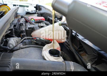 Automechaniker gießt motoröl durch den trichter in den automotor