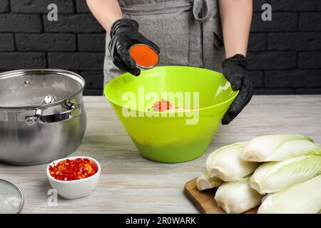 Eine Frau, die scharfen Kohlkimchi auf einem Holztisch zubereitete, drinnen, Nahaufnahme Stockfoto