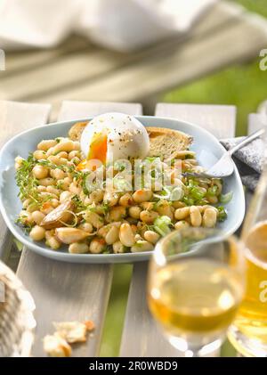 Weißer Haricot-Bohnensalat mit rosa Knoblauch und einem weich gekochten Ei Stockfoto