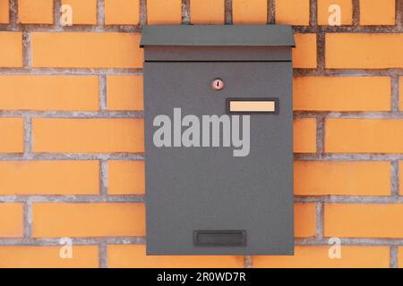 Schwarzer Briefkasten aus Metall an roter Backsteinwand Stockfoto