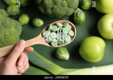 Eine Frau, die einen Löffel Pillen auf verschwommenem Hintergrund hält, Draufsicht. Präbiotische Ergänzungsmittel Stockfoto