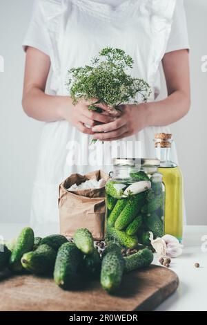 Eine Frau, die Gurken zubereitet und Dill in der Küche hält Stockfoto