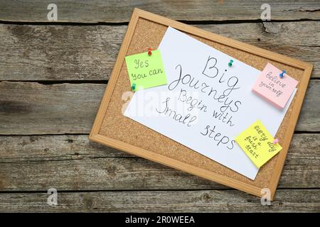 Korkbrett mit motivierenden Zitaten auf Holztisch, Draufsicht Stockfoto