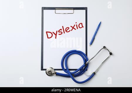 Klemmbrett mit Wort Dyslexia, Stift und Stethoskop auf weißem Hintergrund, Draufsicht Stockfoto