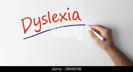 Ein Mann schreibt das Wort Dyslexia auf weißem Hintergrund, Nahaufnahme. Bannerdesign Stockfoto