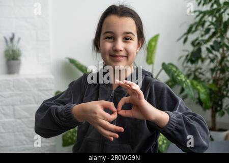 Wunderschönes, lächelndes, taubes Mädchen, das Gebärdensprache benutzt. Stockfoto