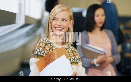 Sie lernt gerne. Eine junge Schülerin, die im Klassenzimmer steht. Stockfoto