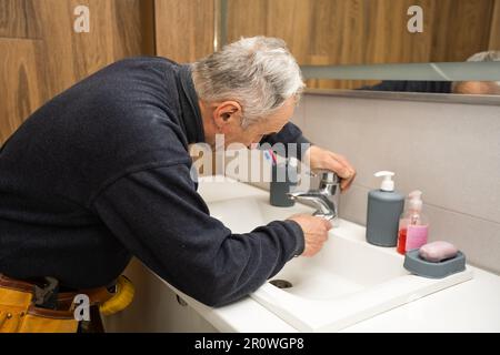Der Klempner repariert gerade einen Wasserhahn mit Wasser im Badezimmer Stockfoto