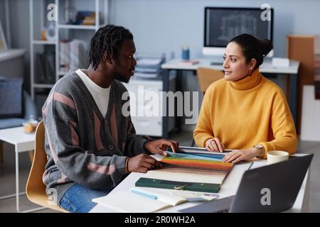 Kollegen diskutieren Farben auf der Palette, während sie sich für das Design für Innenräume während der Teamarbeit im Büro entscheiden Stockfoto