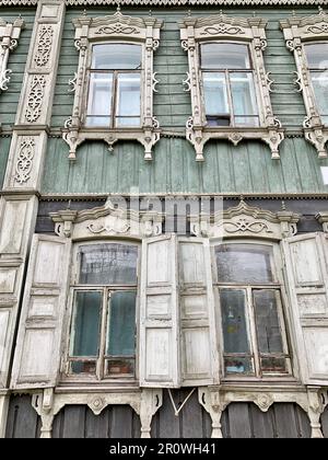 Alte zweistöckige Holzhäuser mit Fenstern in Tomsk, Russland. Heruntergekommene Wohnungen in schlechtem Zustand. Stockfoto