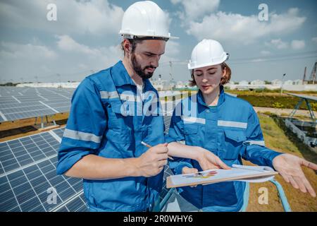 Solaringenieure untersuchen Schaltschrankarrays auf Bauernhöfen anhand von Bauplänen und Zeichnungen visuell, um sicherzustellen, dass Ausrichtung, Oberfläche, Sonnenlicht und zugänglich sind Stockfoto