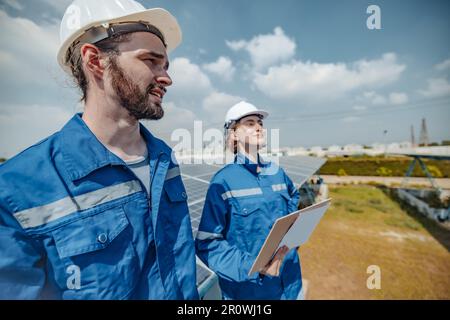 Solaringenieure untersuchen Schaltschrankarrays auf Bauernhöfen anhand von Bauplänen und Zeichnungen visuell, um sicherzustellen, dass Ausrichtung, Oberfläche, Sonnenlicht und zugänglich sind Stockfoto