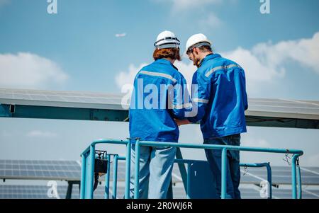 Solaringenieure untersuchen Schaltschrankarrays auf Bauernhöfen anhand von Bauplänen und Zeichnungen visuell, um sicherzustellen, dass Ausrichtung, Oberfläche, Sonnenlicht und zugänglich sind Stockfoto