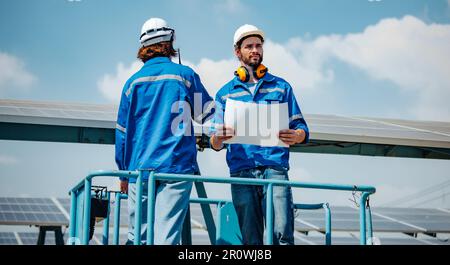 Solaringenieure untersuchen Schaltschrankarrays auf Bauernhöfen anhand von Bauplänen und Zeichnungen visuell, um sicherzustellen, dass Ausrichtung, Oberfläche, Sonnenlicht und zugänglich sind Stockfoto