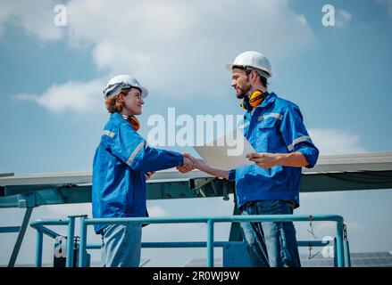 Solaringenieure untersuchen Schaltschrankarrays auf Bauernhöfen anhand von Bauplänen und Zeichnungen visuell, um sicherzustellen, dass Ausrichtung, Oberfläche, Sonnenlicht und zugänglich sind Stockfoto