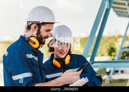 Solaringenieure untersuchen Schaltschrankarrays auf Bauernhöfen anhand von Bauplänen und Zeichnungen visuell, um sicherzustellen, dass Ausrichtung, Oberfläche, Sonnenlicht und zugänglich sind Stockfoto