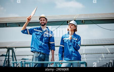 Solaringenieure untersuchen Schaltschrankarrays auf Bauernhöfen anhand von Bauplänen und Zeichnungen visuell, um sicherzustellen, dass Ausrichtung, Oberfläche, Sonnenlicht und zugänglich sind Stockfoto