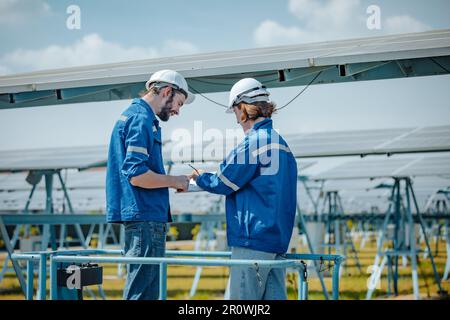 Solaringenieure untersuchen Schaltschrankarrays auf Bauernhöfen anhand von Bauplänen und Zeichnungen visuell, um sicherzustellen, dass Ausrichtung, Oberfläche, Sonnenlicht und zugänglich sind Stockfoto