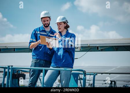 Solaringenieure untersuchen Schaltschrankarrays auf Bauernhöfen anhand von Bauplänen und Zeichnungen visuell, um sicherzustellen, dass Ausrichtung, Oberfläche, Sonnenlicht und zugänglich sind Stockfoto